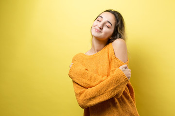 Happy young caucasian femalein an orange sweater lifts a clenched fist up for joy. Success and happiness of the work. Successful person, victory!..	