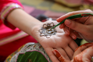 Girl painting henna on the hand