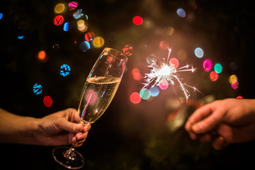Glass with champagne and sparkler on a Christmas tree background