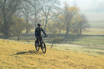 Fototapeta na wymiar Cyclist in pants and fleece jacket on a modern carbon hardtail bike with an air suspension fork. The guy on the top of the hill rides a bike.