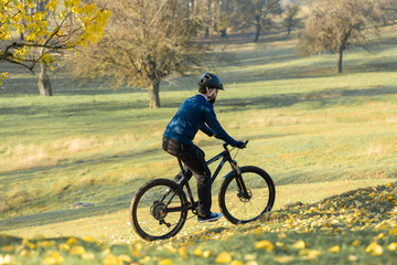 Obraz premium Cyclist in pants and fleece jacket on a modern carbon hardtail bike with an air suspension fork. The guy on the top of the hill rides a bike.