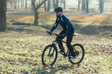 Fototapeta premium Cyclist in pants and fleece jacket on a modern carbon hardtail bike with an air suspension fork. The guy on the top of the hill rides a bike.