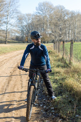 Cyclist in pants and fleece jacket on a modern carbon hardtail bike with an air suspension fork rides off-road.