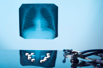 tuberculosis treatment concept. X-ray of the lungs, with pathology, phonendoscope with pills on the table.