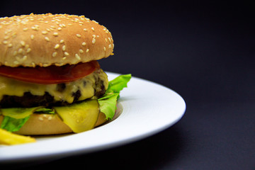Burger with beef cutlet, tomato sauce and french fries on black background