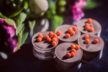 chocolate candies with peonies on a dark mirror background