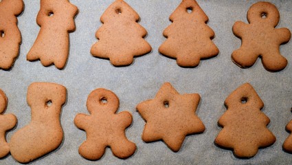 Christmas cookies. Homemade gingerbread cookies in various shapes  on the baking tray. Cookies freshly made at home, golden browned colored cookies before decorating with icing