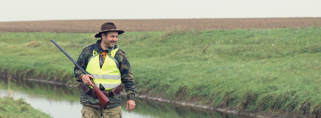 Hunting period, autumn season open. A hunter with a gun in his hands in hunting clothes in the...