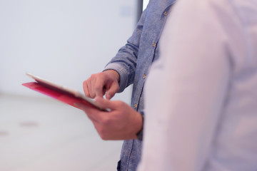 Male college student standing in corridor of university after her class and holding his tablet.