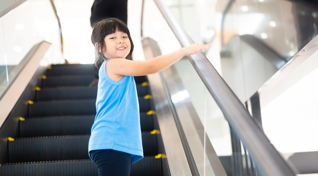 Smiling Little Child Girl Walking To Escalator Alone At Mall.First Time For Little Asian Girl With Escalator.