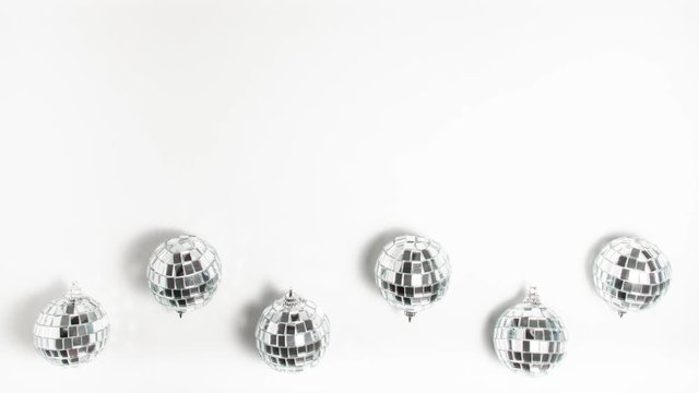 Flat lay top view silver mirror disco balls that spin on white background at the battom. Stop motion animation party concept