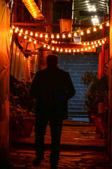 Tbilisi, Georgia A sihouetted man walking in a back alley illuminated by hanging lights.