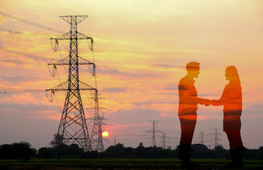 Silhouette Of Two people Shaking Hands With Electricity Pylon at big sunset
