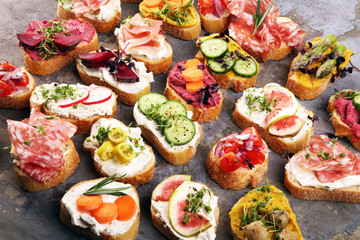 Assorted bruschetta with various toppings. Appetizing bruschetta or brie crostini. Variety of small sandwiches. Mix bruschetta on table