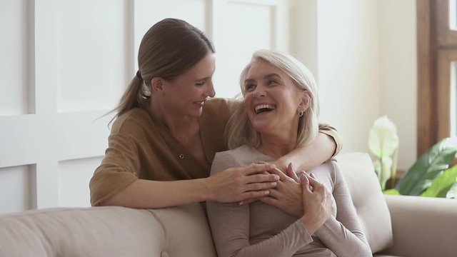 Smiling young woman embracing happy affectionate older retired mother.