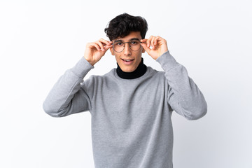 Young Argentinian man over isolated white background with glasses and surprised