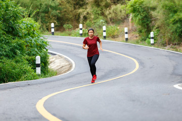 Front of woman runner and runing at the road surround with green forest.