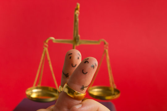 Purposal devorce creative concept. Painted happy fingers smiley in love against red background with court libra