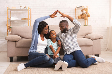 Black parents making symbolic roof of hands above little daughter's head