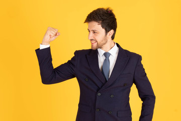 A man in a suit with a tie Handsome looking face with beard In Mad Look, business people are happy by raising their hands to raise their fists. In the yellow background