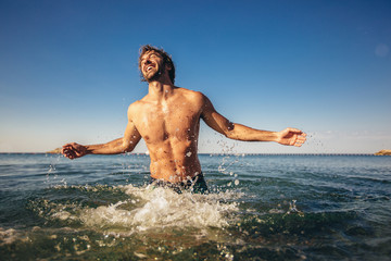 Handsome young man posing on the beach by the sea