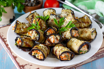 Appetizer stuffed with eggplant. Fried eggplant roll with chicken and vegetables in a plate on a wooden kitchen table.