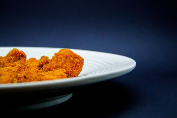 Chicken nuggets on white plate on black background