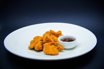 Chicken nuggets on white plate on black background
