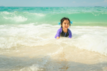 Lovely Asian little girl plays alone on beach with sea wave and she look very happy and fun.