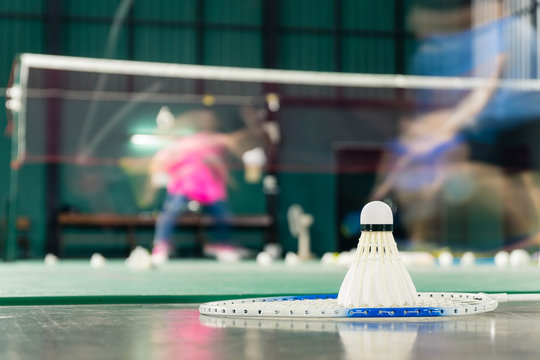 shuttlecock resting on a badminton racket with badminton player are competiting