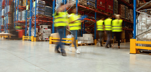 Warehouse workers walking in warehouse, blurred image