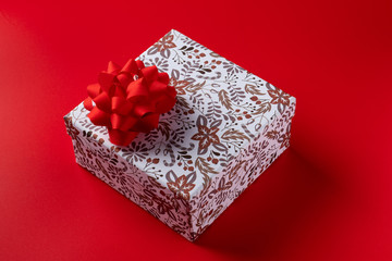 gift box with a red bow on a red background for the holiday. Copy space