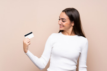 Fototapeta premium Young woman over isolated background holding a credit card