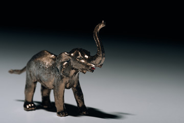 Obraz premium Golden toy elephant with blood on tusks on grey background, hunting for tusks concept