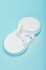 Top view of toy polar bear on plastic coffee lids on blue background, animal welfare concept