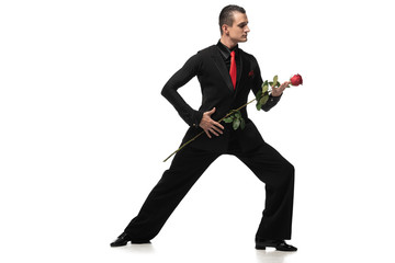 sensual dancer in elegant black suit performing tango with black rose on white background