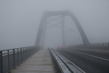 Iron bridge in the dense fog of autumn