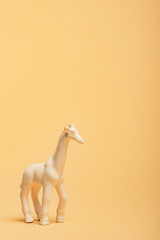 Obraz premium White toy giraffe on yellow background, animal welfare concept