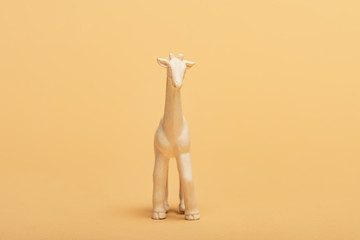White toy giraffe on yellow background, animal welfare concept