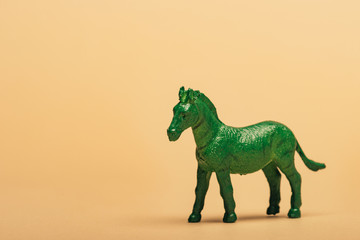 Green toy horse on yellow background, animal welfare concept