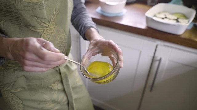Caucasian woman hands beating eggs with fork in home kitchen, close up