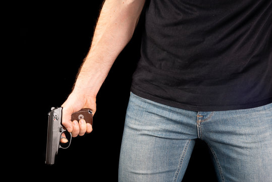A man with a gun in his hand on a black background. Killer with a gun