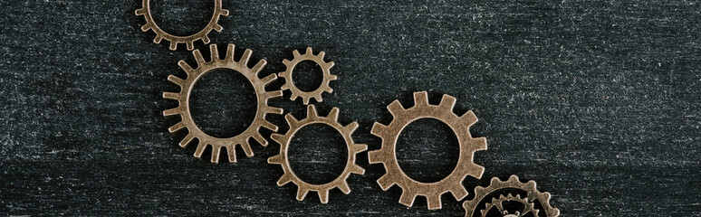 top view of retro metal gears on dark wooden background, panoramic shot