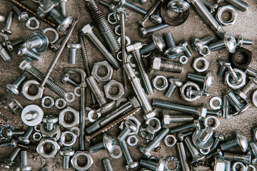 top view of metal screws and nails scattered on grey background