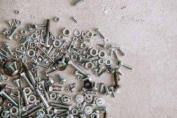 top view of metal screws and nails scattered on grey background