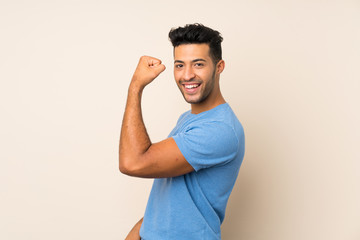 Young handsome man over isolated background doing strong gesture
