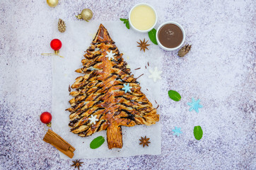 Christmas tree pastry (cake, pie) with cinnamon and cocoa filling served with chocolate sauces on a stone background.  Dessert for Christmas and New Year.