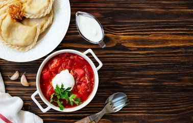 Eastern European food Ukrainian, Russian, Polish. Borscht and Varenyky, Vareniki. Traditional beetroot soup borscht and dumplings with potatoes served with sour cream and parsley on a wooden table