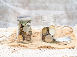 Coins in glass jar isolated on fabric    background with copy space. Saving money concept.
