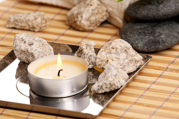 Tea candle and decorative stones on a bamboo mat